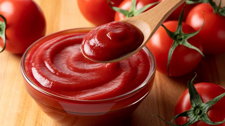 Semangkuk saus tomat dengan tomat segar di sampingnya