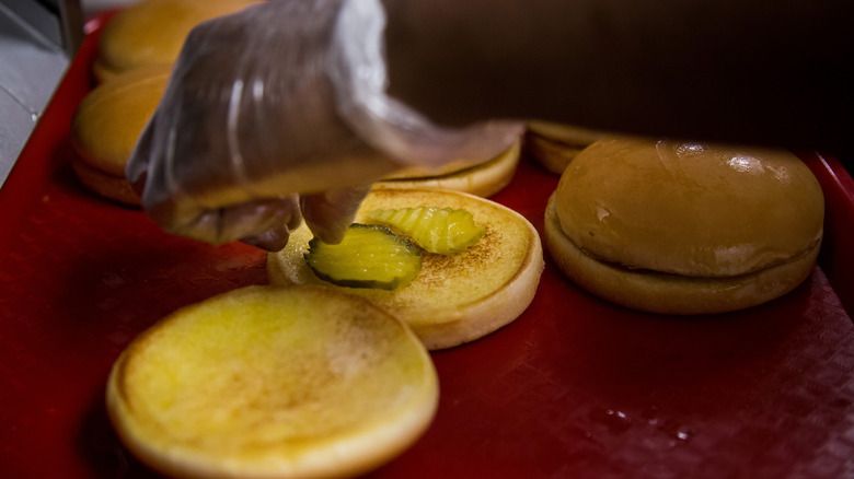 Radnik u rukama u rukavicama sastavlja pileće sendviče