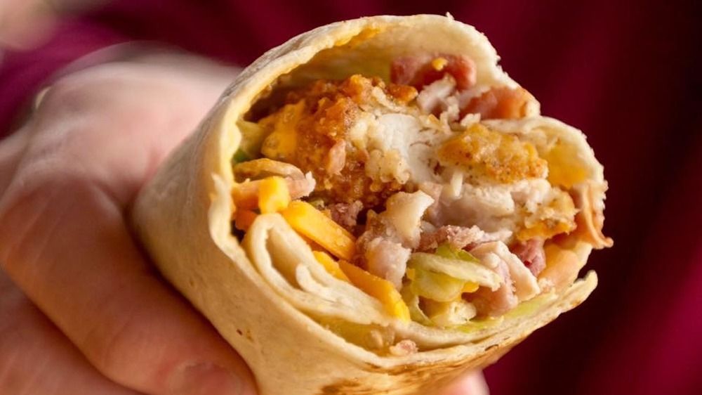 Dłoń trzymająca chrupiące burrito z kurczakiem Taco Bell