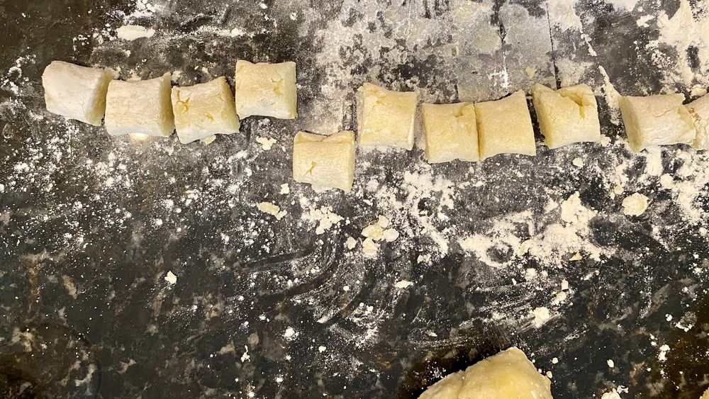 pâte à gnocchis coupée en morceaux individuels sur un comptoir en pierre fariné