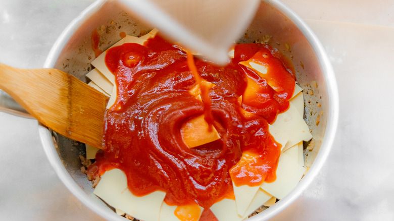 Verser la sauce sur les nouilles à lasagne