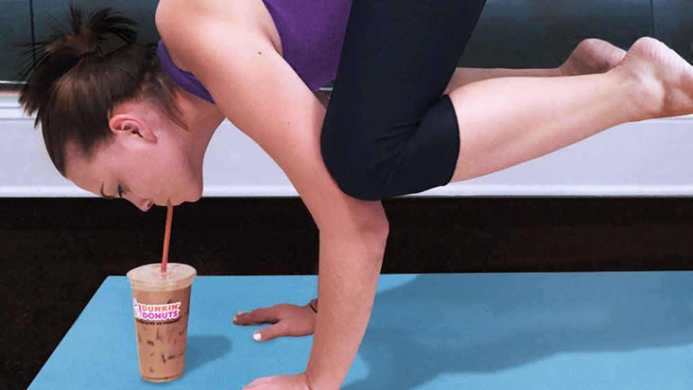 Wanita dalam pose yoga menyeruput Dunkin
