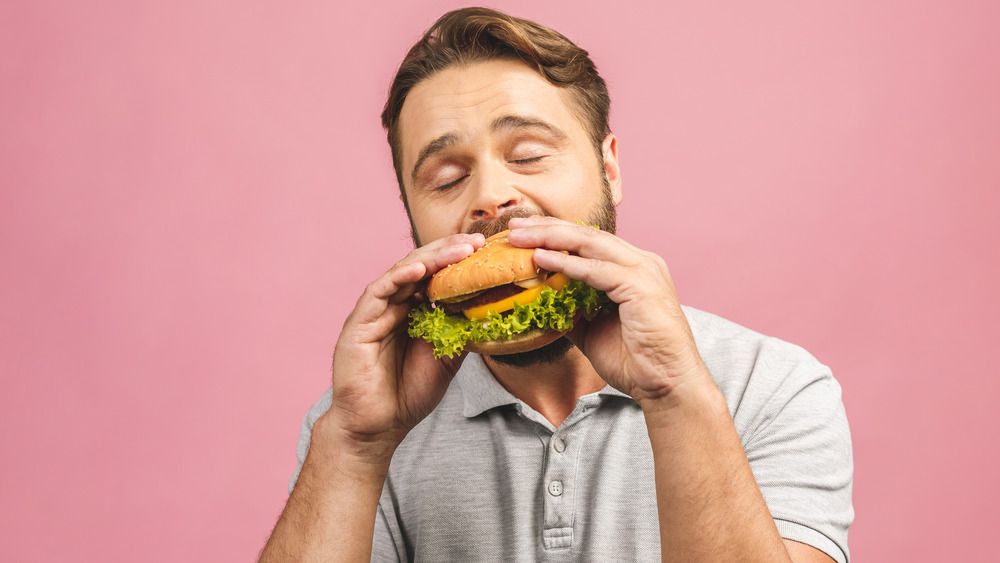 Человек ест гамбургер