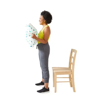 枕椅子でスクワットに立っている女性